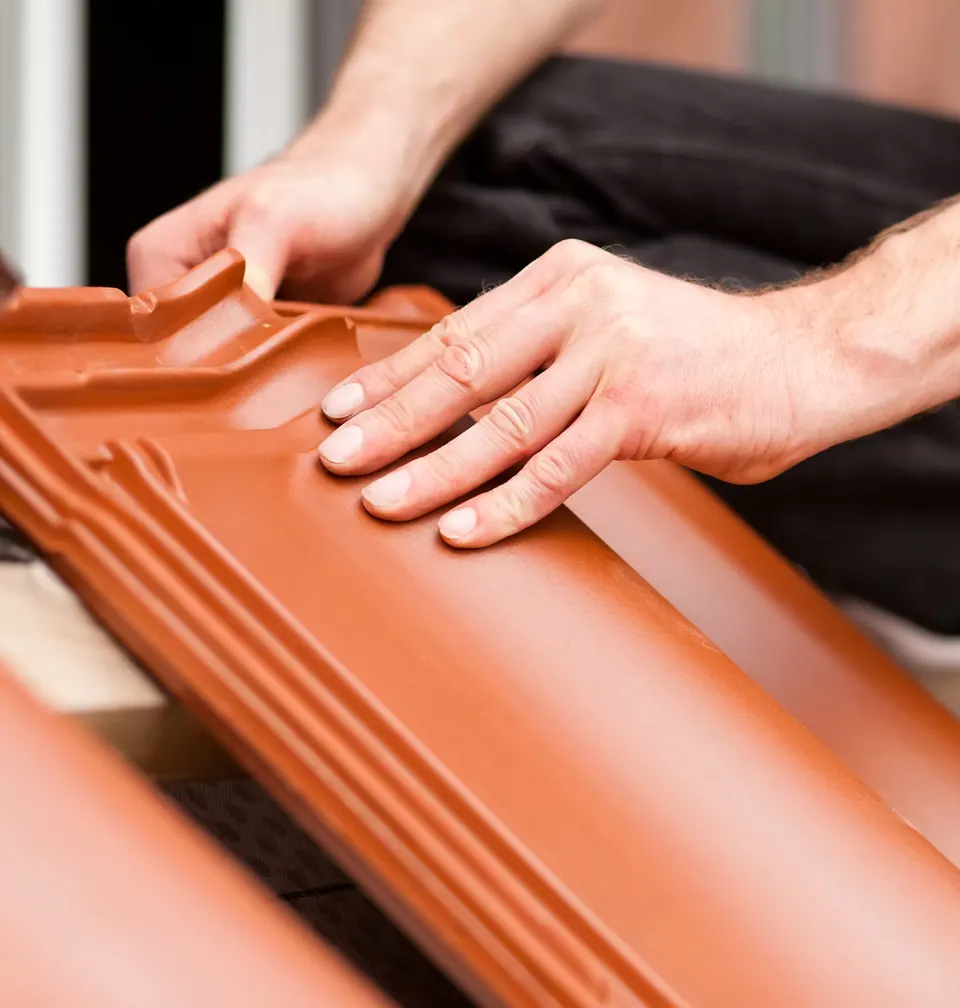 Hands fitting a clay roof tile